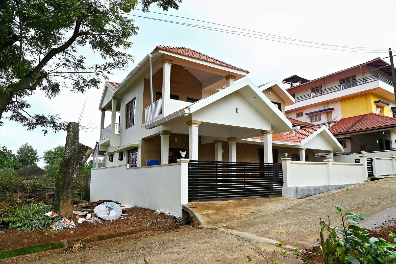 Side view of a two-storey tiled-roof home with car porch built by Matrix Realty