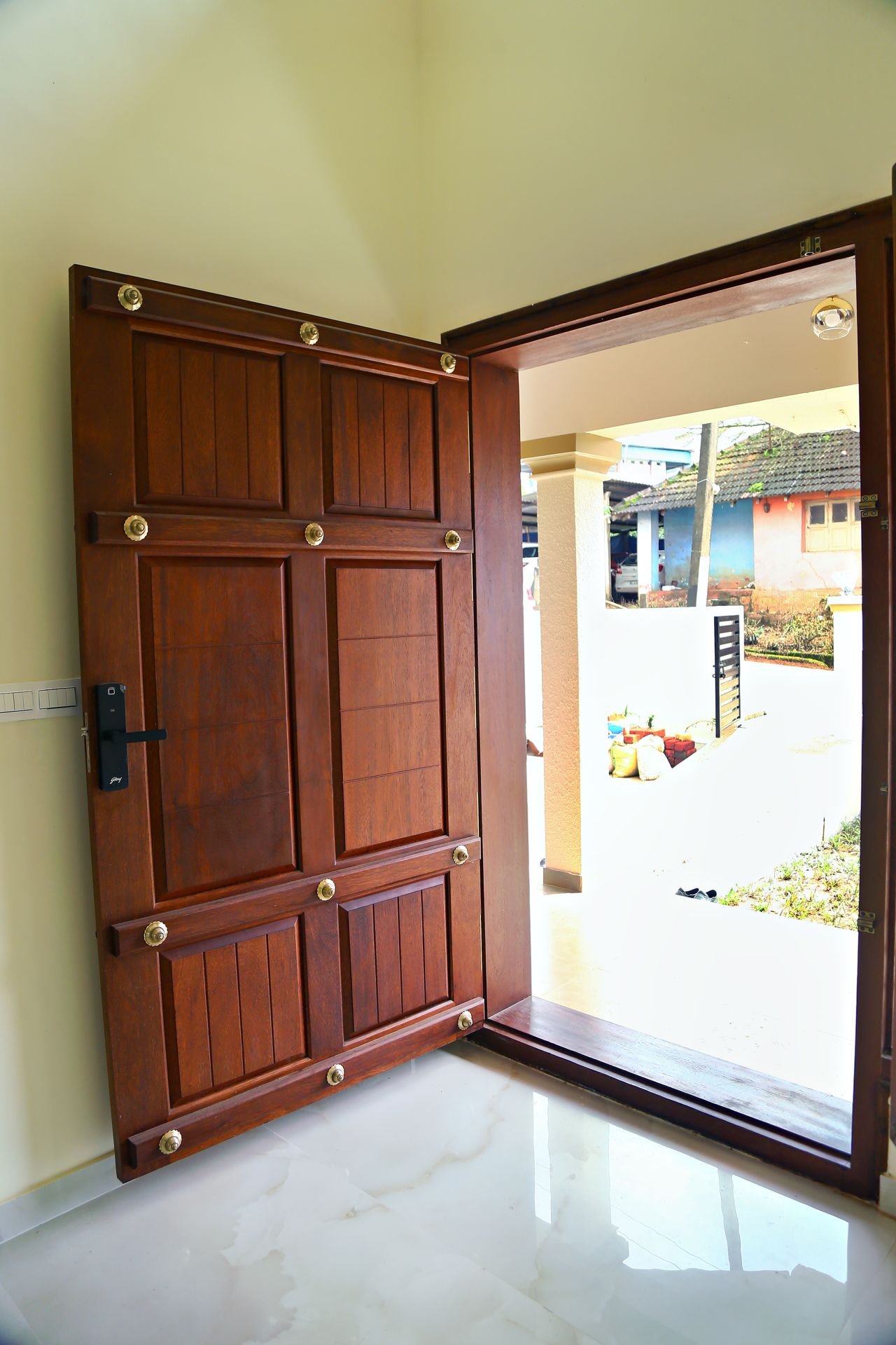 Solid teak main door with brass studs and digital lock, view from inside